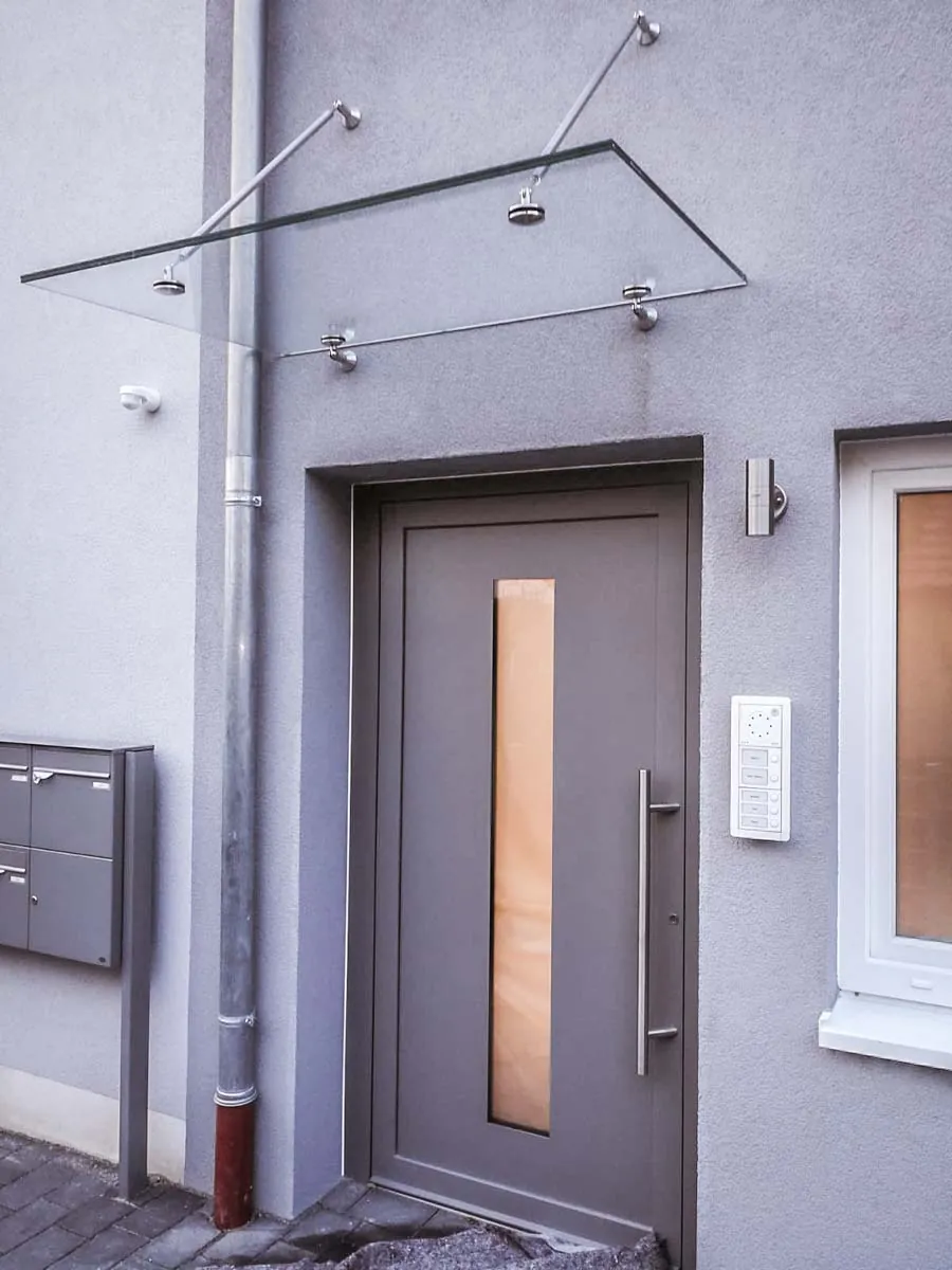 Glasvordach aus Edelstahl mit Zugstäben an der Haustür, Perspektive