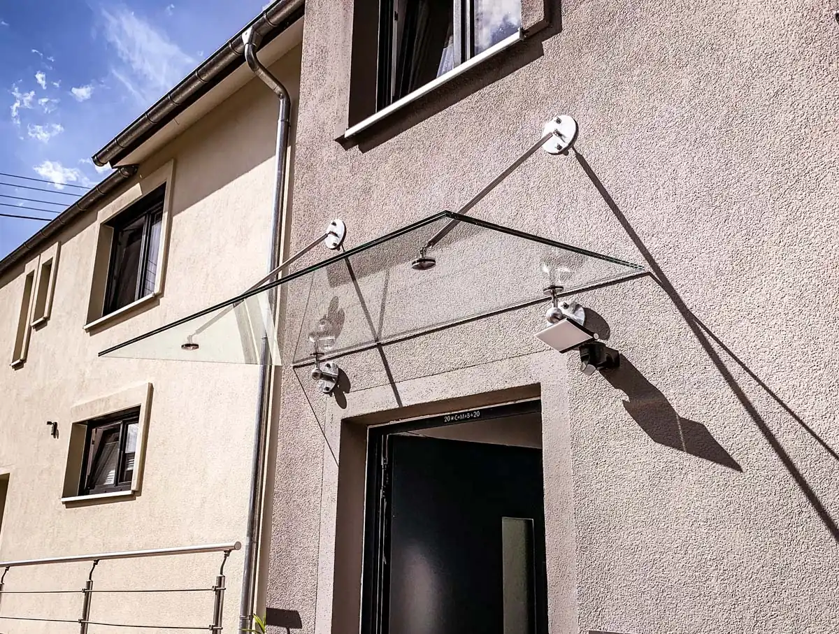 Glasvordach aus Edelstahl mit Zugstäben und Punkthaltern am Eingang