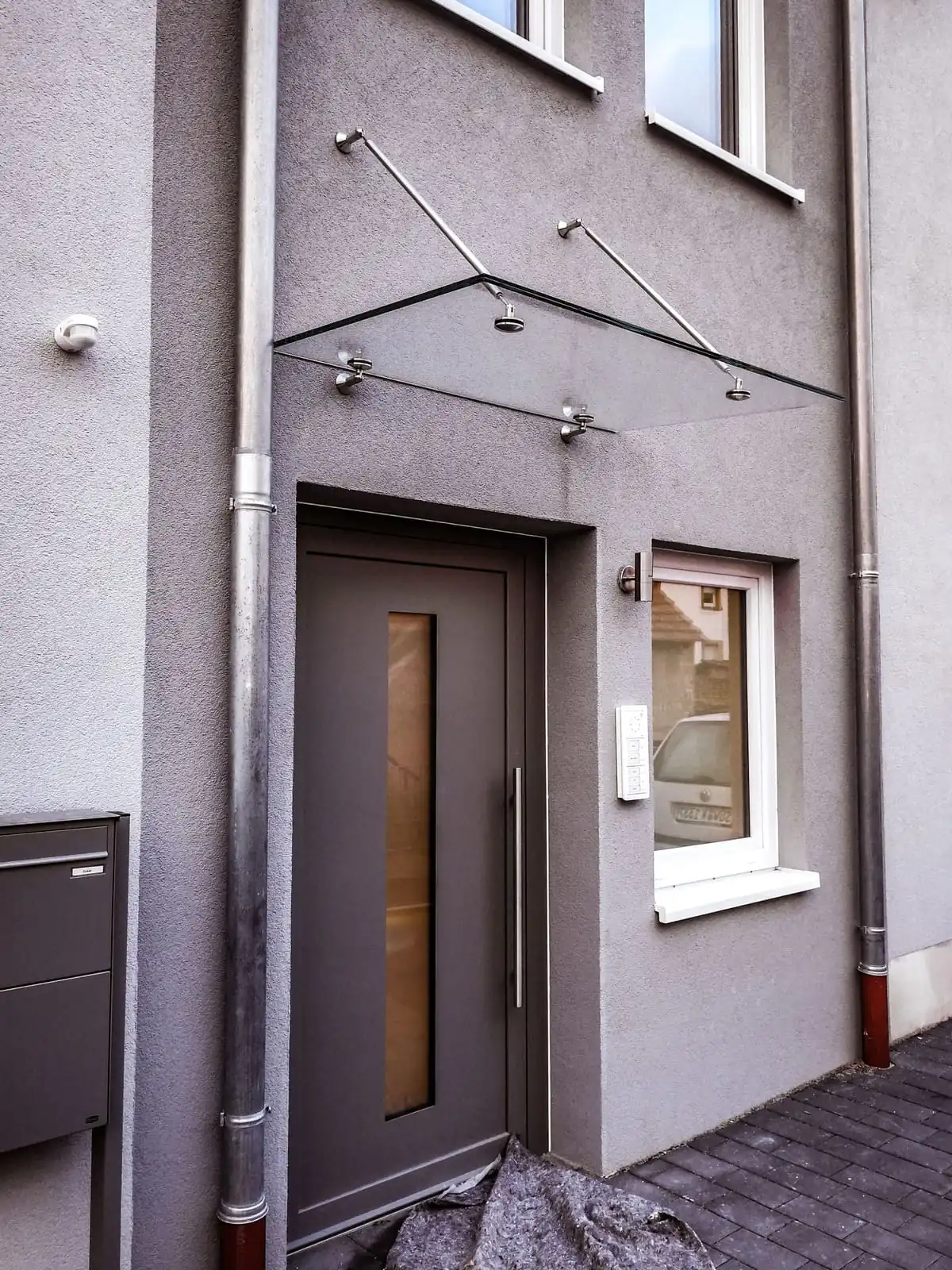 Glasvordach aus Edelstahl mit Zugstäben und Punkthaltern an der Haustür