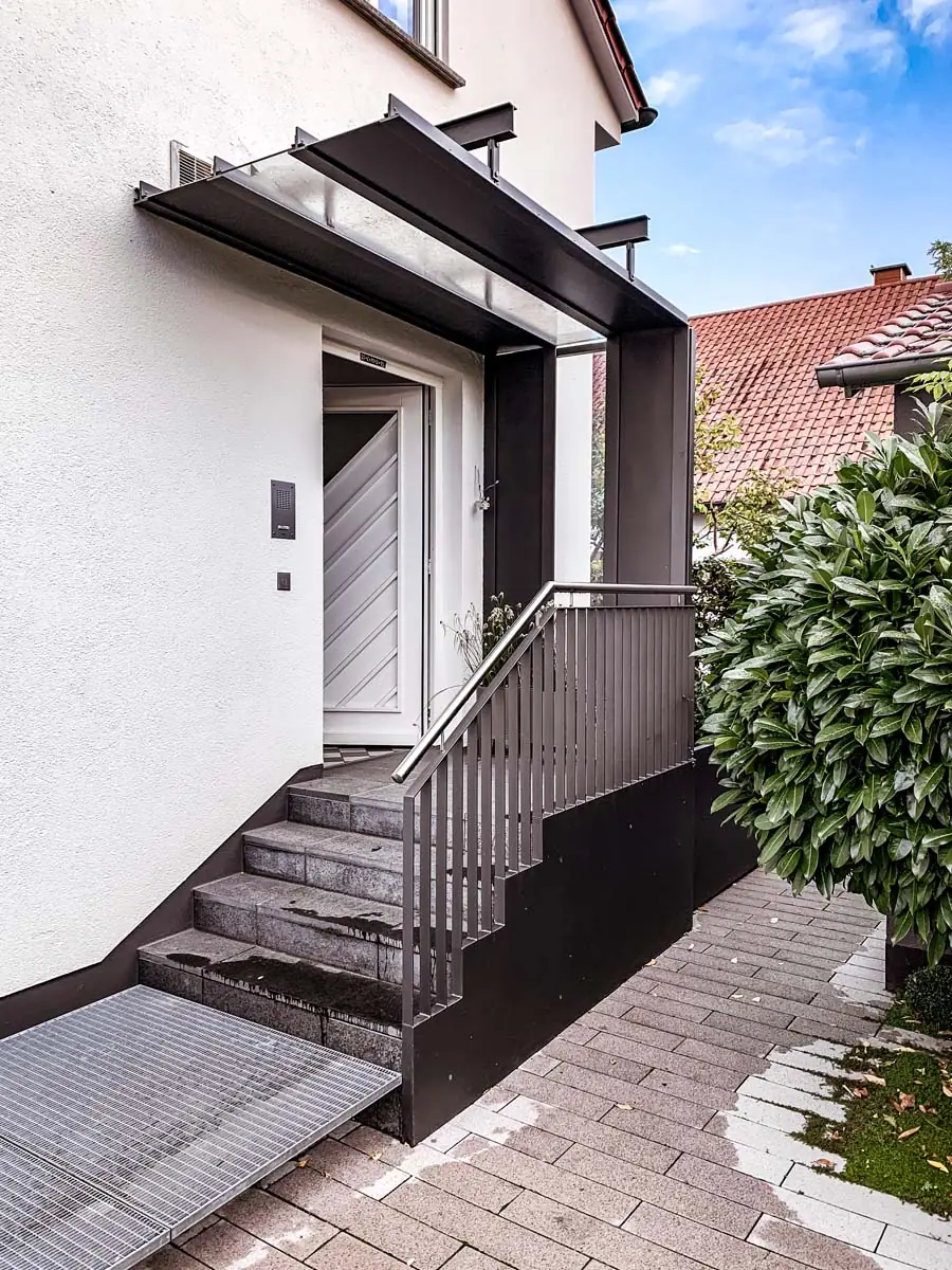 Vordach aus Stahl mit Glasdach und Geländer in Anthrazit am Eingang