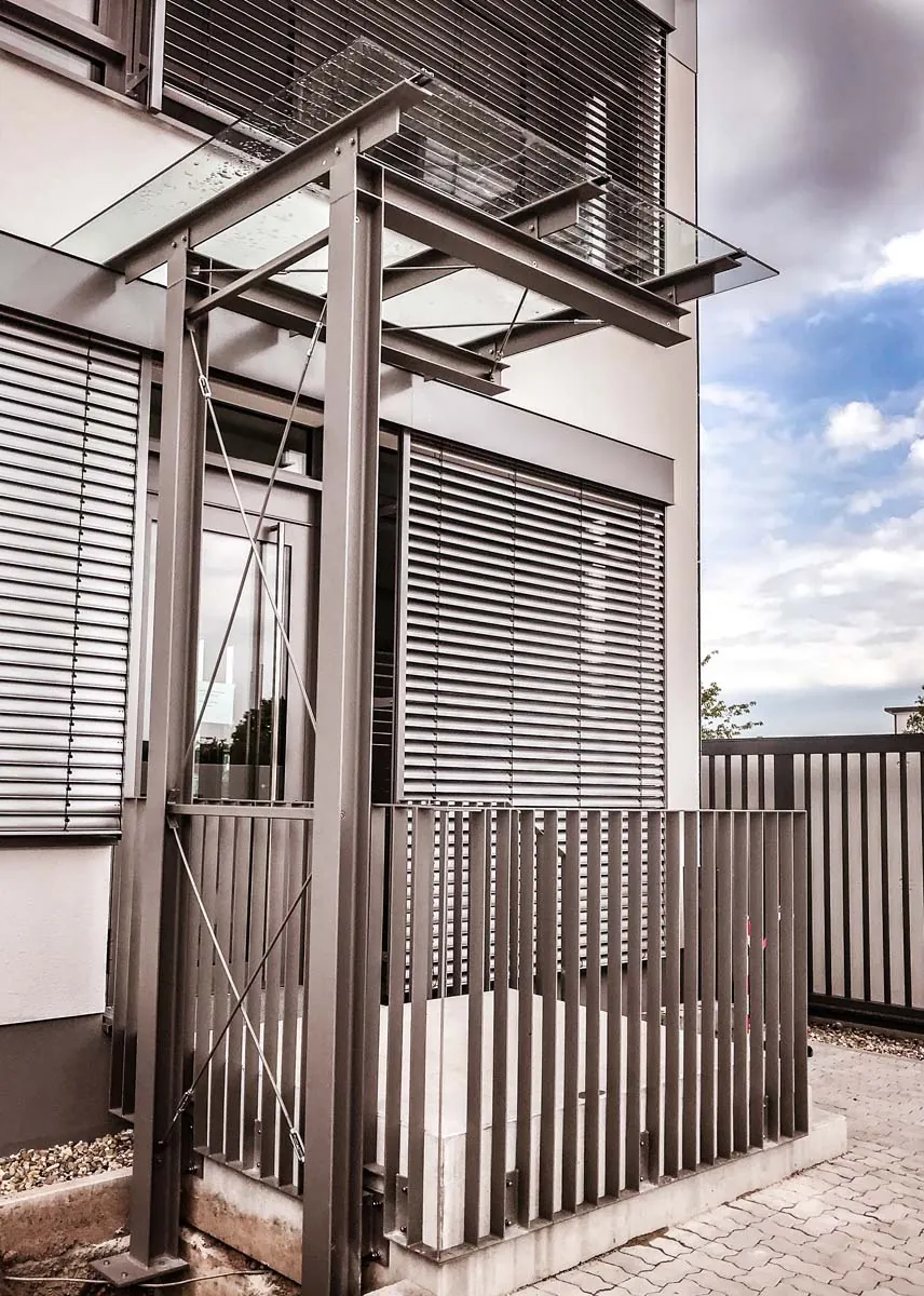 Vordach aus Stahl mit Glasdach und Lamellen-Sichtschutz am Eingang