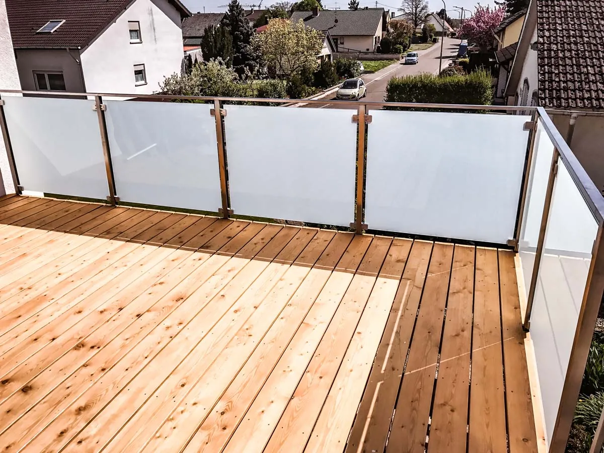 Balkongeländer aus Edelstahl mit Milchglas an Holzterrasse mit Sichtschutz