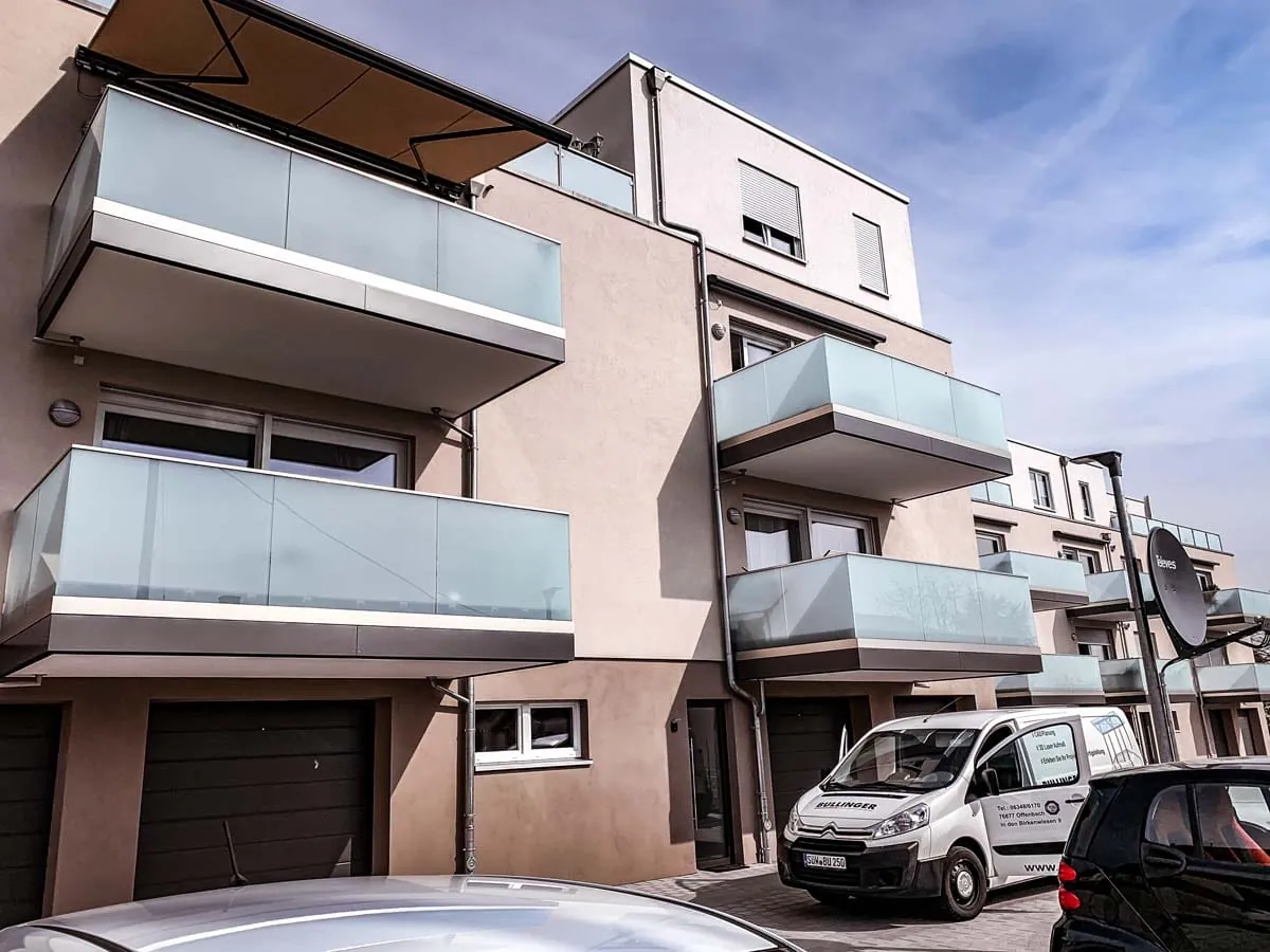 Balkongeländer aus Milchglas mit Edelstahlrahmen am Mehrfamilienhaus