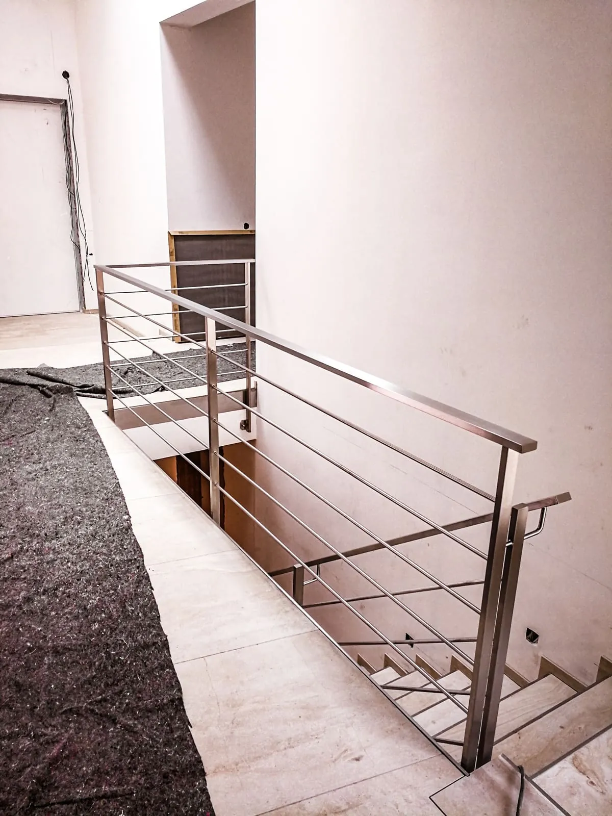 Edelstahlgeländer mit Horizontalstäben an Galerie und Treppenabgang innen