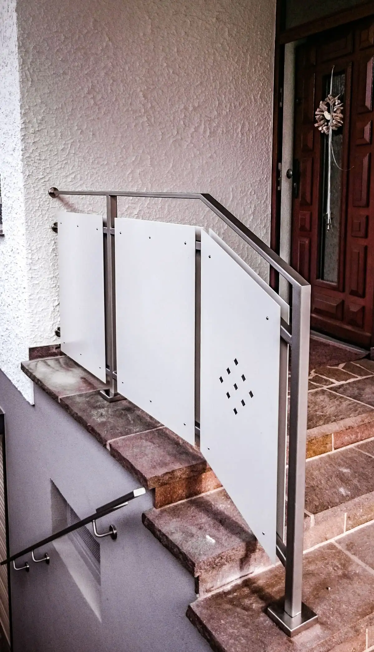 Treppengeländer aus Edelstahl mit Blechfüllung im Rautenmuster am Eingang
