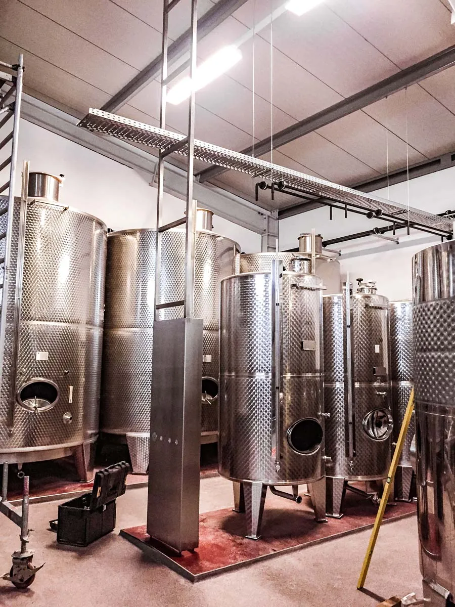Weintanks aus Edelstahl in der Kellerei mit Leitungen