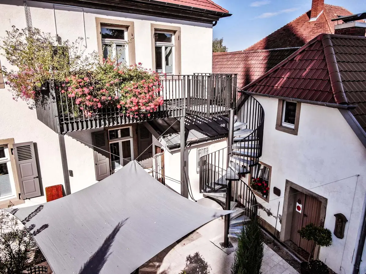 Spindeltreppe im Innenhof eines Altbaus mit Sonnensegel, Drohnenaufnahme